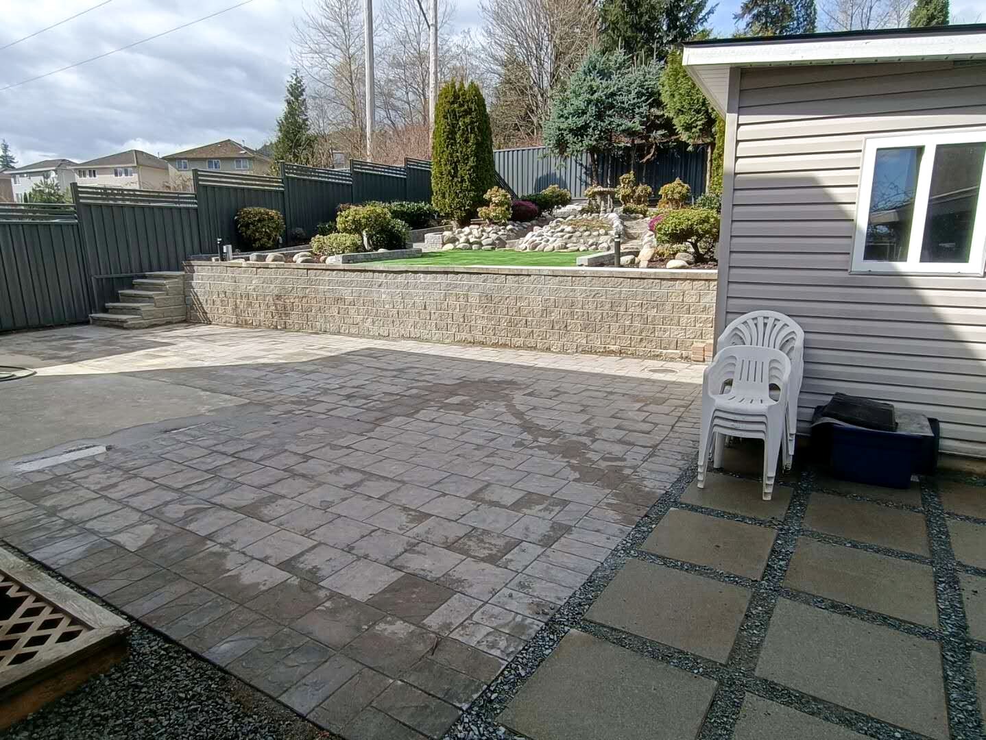 Established residential paver patio with retaining wall and landscaped yard